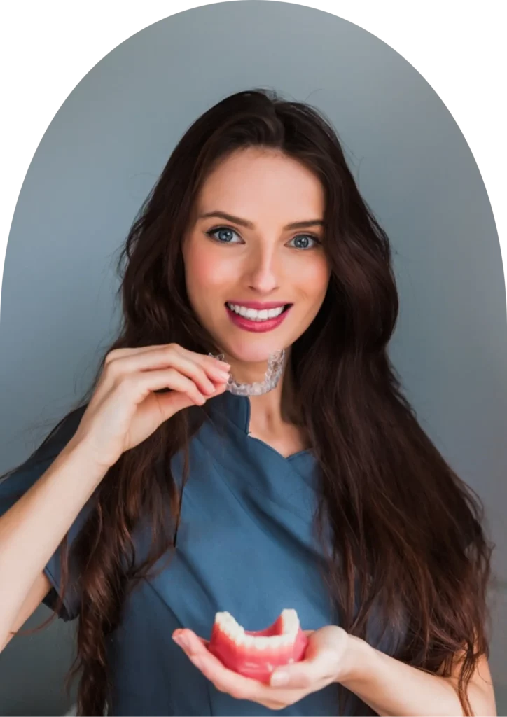 A beautiful woman smiling while holding her clear aligner after her dental treatment at beyondental